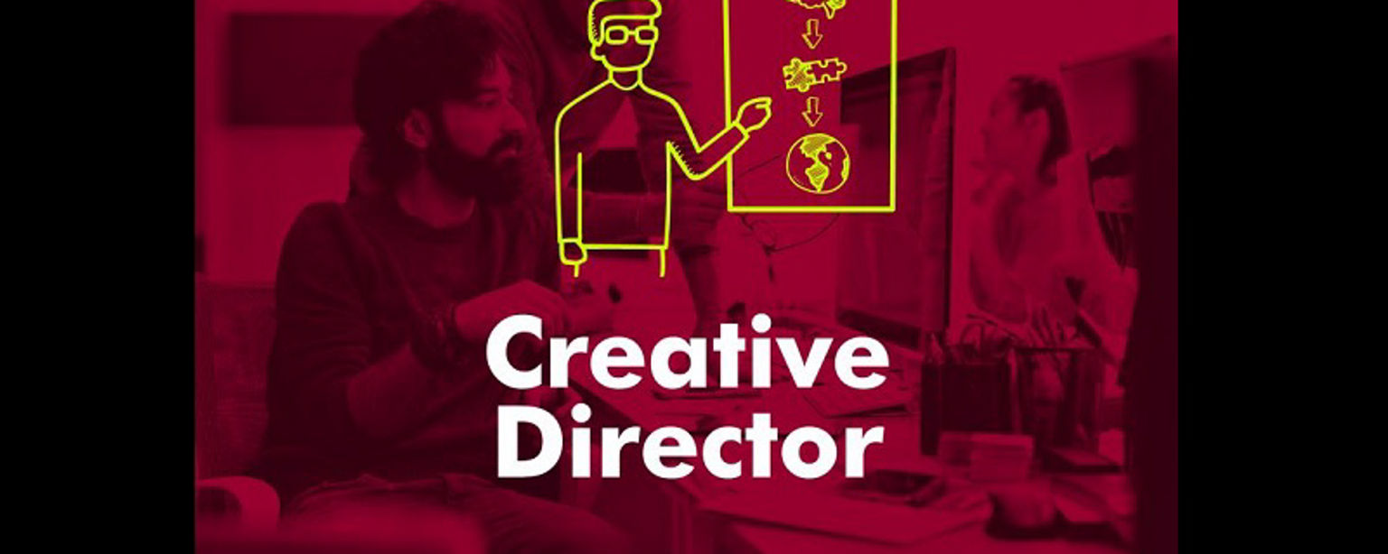 A creative director works in an office environment as a coworker looks on; the words "Creative Director" are overlaid on the image.